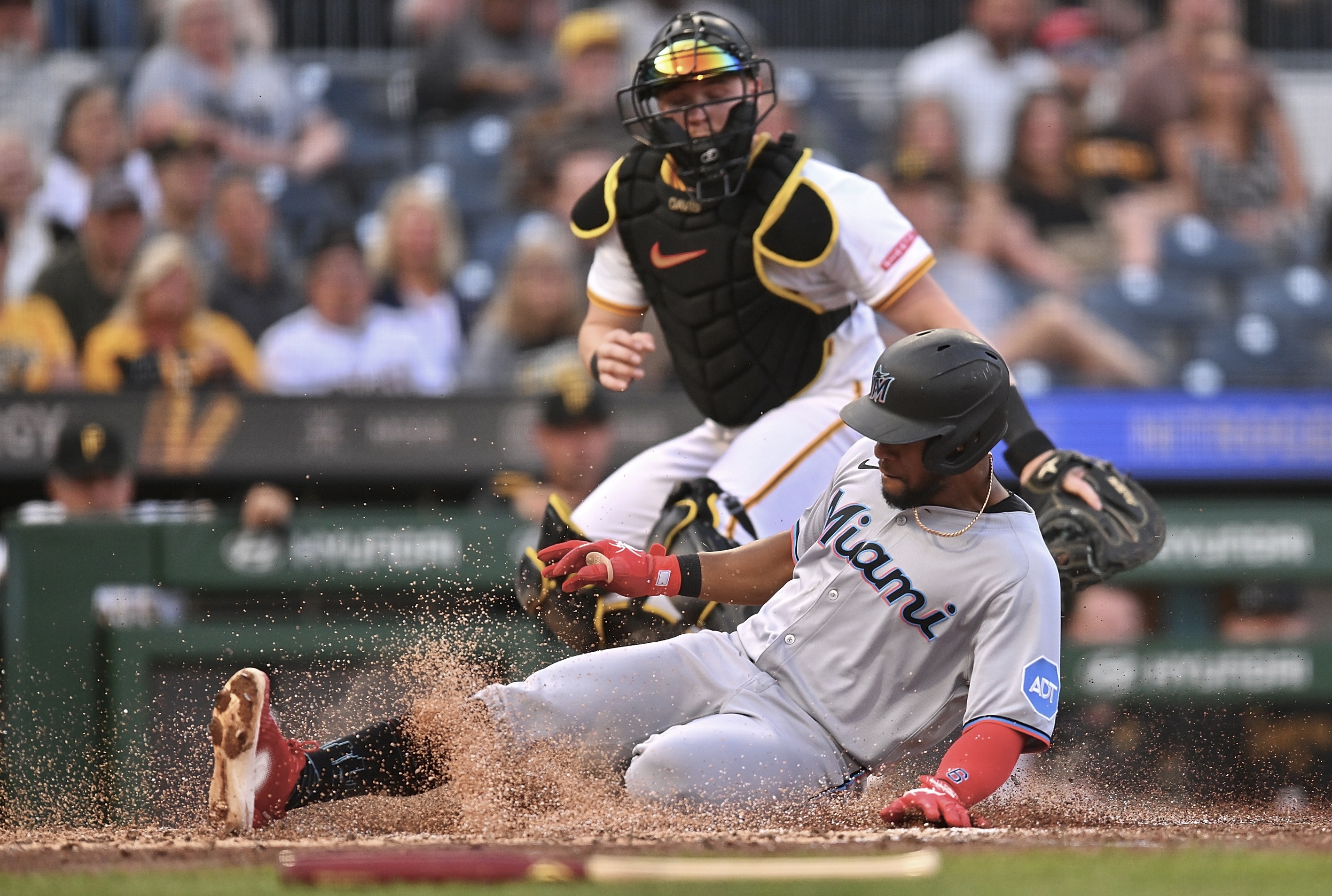 The Marlins' Otto Lopez slides safely past Henry Davis in the fourth inning Tuesday night at PNC Park.
