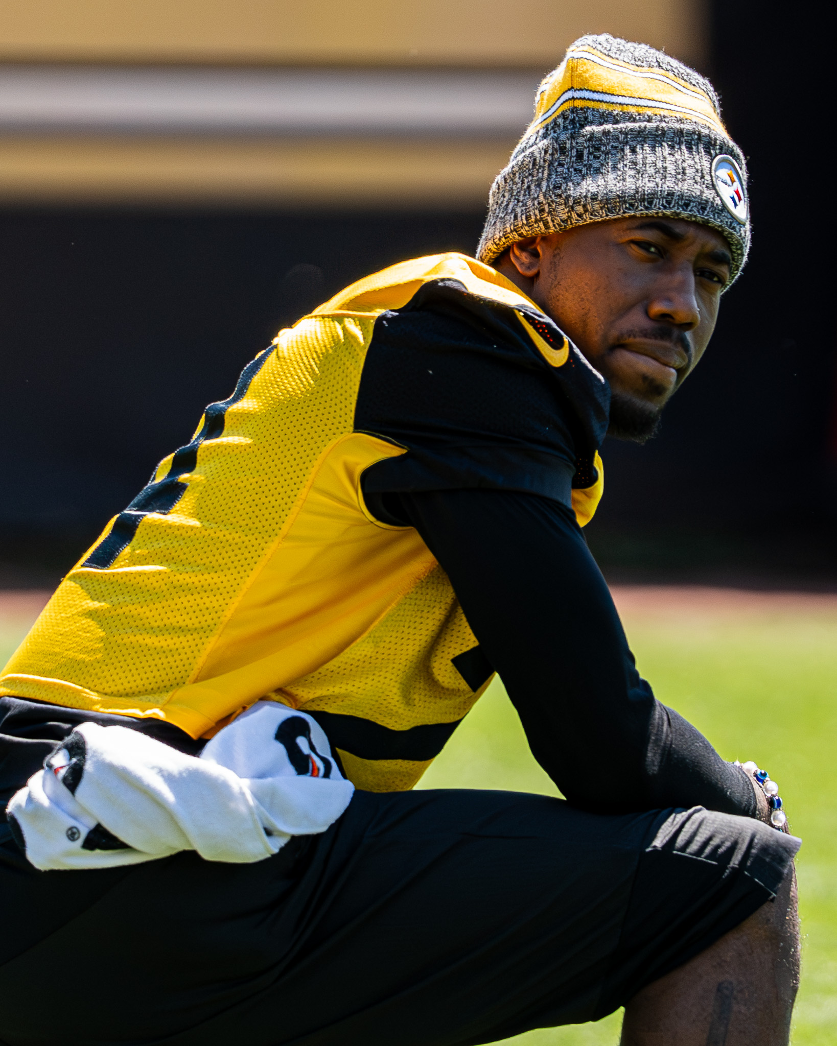 Joey Porter Jr. kneels alongside a few teammates as the team gets set to begin their stretching period.